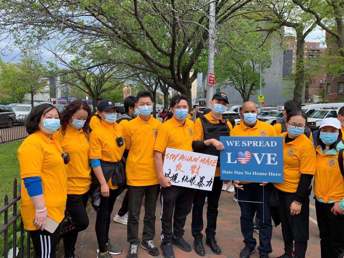 Participants wearing orange shirts pose together; one sign reads “We Spread LOVE.”