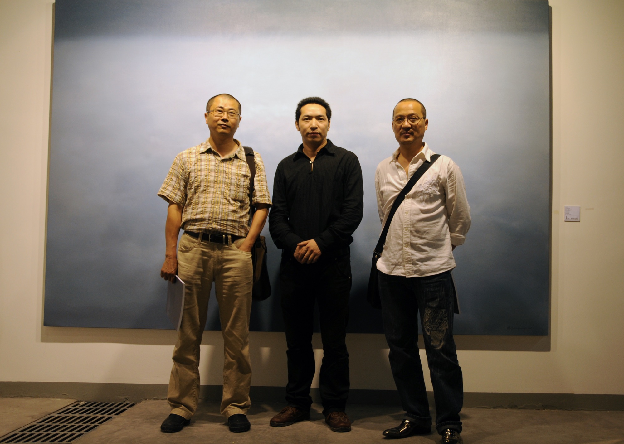 Three people posing in front of a painting at A Single Thread.